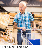 old age senor examines bakery products in the grocery section of the supermarket. Стоковое фото, фотограф Татьяна Яцевич / Фотобанк Лори