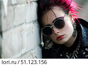 Young punk woman with pink hair leaning against brick wall. Стоковое AI-изображение, AI-художник Иван Рябоконь / Фотобанк Лори