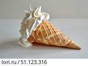 Delicious whipped cream overflowing from waffle cone on white background. Стоковое AI-изображение, AI-художник Иван Рябоконь / Фотобанк Лори