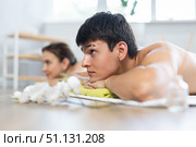 After massage, guy lies on white blanket on floor. Blurry unrecognizable clients girl in background. Стоковое фото, фотограф Яков Филимонов / Фотобанк Лори