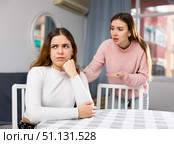 Upset woman sitting at home table with disgruntled woman behind. Стоковое фото, фотограф Яков Филимонов / Фотобанк Лори
