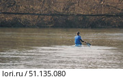 A kayaker paddles vigorously through the calm waters of the river, sending drops flying from the paddle blade. Back view of an athlete in a kayak. Training before the competition. Стоковое видео, видеограф Воловодов Владимир / Фотобанк Лори