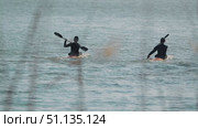 Two kayakers float on calm waters, paddling in unison. Young athletes against the shimmering surface of the lake. Training before the competition. Стоковое видео, видеограф Воловодов Владимир / Фотобанк Лори