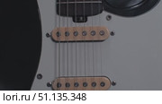 Close-up of the pickups and strings of an electric guitar, showing the intricate details of the fittings. The white finish contrasts nicely with the black deck. Стоковое видео, видеограф Воловодов Владимир / Фотобанк Лори