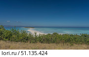A sandbar winds through the aquamarine ocean to a small island. Silhouettes of boats near the shore, people on the beach. Green vegetation in the foreground. Blue sky, clouds. Madagascar. Nosy Iranja. Стоковое фото, фотограф Вера Ивановна Кубарева / Фотобанк Лори
