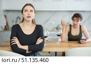 Upset middle-aged woman sitting at the kitchen table with her back to another lady quarreling to her. Стоковое фото, фотограф Яков Филимонов / Фотобанк Лори