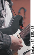 A close-up of a person playing an electric guitar, wearing a plaid shirt over a white tee. The focus is on their fingers strumming the strings, showcasing musical passion. Стоковое видео, видеограф Воловодов Владимир / Фотобанк Лори