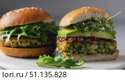 Gourmet vegan burger featuring crisp sprouts, creamy avocado, zesty sauce nestled on sesame bun with peppery arugula side. Стоковое AI-видео, аниматор Юрий Поздников / Фотобанк Лори