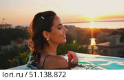 A woman smiles while relaxing in a pool during a stunning sunset at a coastal resort. Стоковое AI-видео, аниматор Данила Большаков / Фотобанк Лори