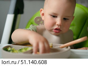 Toddler enjoying first foods in highchair. Стоковое фото, фотограф Скоробогатова Е. / Фотобанк Лори