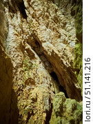 Dark cave view from inside with a lumen. Stalactites and stalagmites inside the stone grotto. Colorful stones in the cave. Lighting electricity beauty of the cave. (2019 год). Стоковое фото, фотограф Наталия Кирсанова / Фотобанк Лори