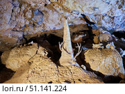 Dark cave view from inside with a lumen. Stalactites and stalagmites inside the stone grotto. Colorful stones in the cave. Lighting electricity beauty of the cave. (2019 год). Стоковое фото, фотограф Наталия Кирсанова / Фотобанк Лори