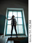 The girl is standing inside an industrial or residential building. A huge old window, an unkempt building. Women's clothing style is free. Стоковое фото, фотограф Наталия Кирсанова / Фотобанк Лори
