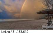 Beautiful double rainbow over the ocean. Evening light. There are sun beds and umbrellas on the sandy beach. The sea waves are foaming. Blue sky, clouds. Malaysia. Borneo. Kota Kinabalu. (2023 год). Стоковое фото, фотограф Вера Ивановна Кубарева / Фотобанк Лори