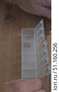 The male opens a plastic tablet organizer and sorts capsules into cells by day of the week to distribute the daily dosage. Стоковое видео, видеограф Дмитрий Цветков / Фотобанк Лори