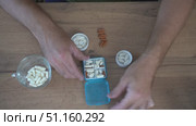 View from above. A man fills a tablet organizer with pills and capsules for the day, arranging them in cells. Стоковое видео, видеограф Дмитрий Цветков / Фотобанк Лори