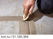 A craftsman carefully grouts the joints between floor tiles, ensuring a smooth and professional finish. Стоковое фото, фотограф Коханова Наталья / Фотобанк Лори