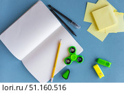 Back to School Supplies with Notebook, Fidget Spinner, Sticky Notes and Pens on Blue Background.Flat lay composition of school supplies on a blue desk. Open squared notebook with pencil, pens, sticky notes, colorful fidget spinner and highlighters. Creative back to school background, education concept, stationery for students and kids. Стоковое фото, фотограф Анастасия Мерчик / Фотобанк Лори