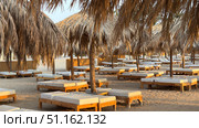 Tropical beach resort scene at sunrise with beach chairs and umbrellas Beautiful panoramic beach. Chairs on the sandy beach near the sea. Summer holiday and vacation concept for tourism. Inspirational tropical landscape. Tranquil scenery, relaxing beach, tropical landscape design. Стоковое фото, фотограф Zita Khasanova / Фотобанк Лори