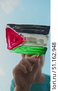 Child paints flag of Palestine in bright colors on glass against background of serene azure sky, embodying security and serenity. Стоковое видео, видеограф Strunov David / Фотобанк Лори