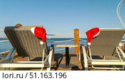 Santaclaus or Santa Claus hat on a sun lounger by the sea. Стоковое фото, фотограф Igor Skripachev / Фотобанк Лори