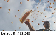 Man gradually empties substantial quantity of dried ground peas or chickpeas from container onto clear glass in open air. Low angle. Стоковое видео, видеограф Strunov David / Фотобанк Лори