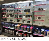 A photo of an electronics store window with computer components. The glass shelves display Nvidia video cards of various models, sound cards, and cooling devices. At the bottom of the rack are power supplies of various capacities in branded packaging. The products are neatly arranged with price tags and information cards. The lighting of the window emphasizes the modern look of the equipment. The image reflects the atmosphere of a specialized computer components store, where you can buy the necessary equipment to assemble or upgrade a personal computer. (2019 год). Редакционное фото, фотограф Анна Кривицкая / Фотобанк Лори