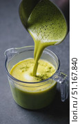 Vibrant matcha latte pouring from metallic pot into glass jug, showcasing artisan brewing technique with rich green liquid against shadowy background. Стоковое AI-видео, аниматор Юрий Поздников / Фотобанк Лори