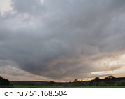 Dramatic thunderous sunset sky with dark huge rain clouds over green forest. Стоковое фото, фотограф irisff / Фотобанк Лори