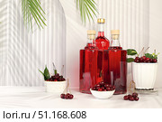 Homemade hard cherry cider in bottles on elegant background, still life with alcoholic drinks and fresh cherries, home winemaking concept, minimalist banner for bar, advertising banner for cafe. Стоковое фото, фотограф Светлана Балынь / Фотобанк Лори