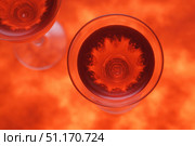Top view of two wine glasses filled with a deep red drink, set against a vibrant red-orange background that creates a fiery, festive atmosphere. The symmetrical patterns formed inside the glasses resemble blooming flowers or fireworks, adding a dynamic visual element. This image evokes feelings of celebration and warmth, making it suitable for New Year’s Eve, Valentine’s Day, and Defender of the Fatherland Day in Russia. Ideal for illustrating toasts, romantic dinners, or patriotic gatherings where red, symbolic of love and courage, takes center stage. Стоковое AI-изображение, AI-художник Ксения Чунаева / Фотобанк Лори