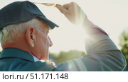 An elderly man reflects on memories while holding a cherished photograph at a crowded park event. Стоковое AI-видео, аниматор Данила Большаков / Фотобанк Лори