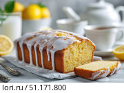Homemade lemon drizzle cake with icing. Classic lemon pound cake with citrus glaze and zest. Whole loaf, side view, close up. Fresh homemade baked dessert with lemon slices. Blurred tea set background. Стоковое AI-изображение, AI-художник Марина Демидюк / Фотобанк Лори