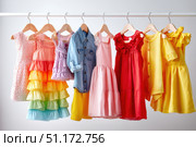 Colorful collection of baby dresses, isolated on a white background. Different styles and colors clothes for baby girls. Rainbow ruffle skirt, denim shirt top, party gown, cotton short-sleeve dresses. Стоковое AI-изображение, AI-художник Марина Демидюк / Фотобанк Лори