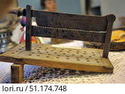 An old household item is presented - a hand-made wooden base with a fixed metal blade, reminiscent of a primitive device for cutting or processing. The product is made of wood and iron, with noticeable traces of time and corrosion. Perforation on the wooden surface indicates a functional purpose - perhaps for holding or airing the material. Such items are ethnographic exhibits and are of interest as part of the history of everyday peasant labor. The atmosphere of the photo conveys the spirit of antiquity, a museum exhibition and traditional way of life. Стоковое фото, фотограф Анна Кривицкая / Фотобанк Лори