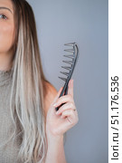 Woman combing hair extensions comfortably using wide tooth comb to prevent tangles and hair breakage. Стоковое фото, фотограф Svetlana Golovco / Фотобанк Лори