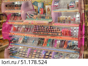 A display case with decorative cosmetics of the Essence brand in the store. The shelves are decorated in bright pink and purple tones, the products are laid out in sections. On the upper shelves you can see foundation creams, powders and highlighters, as well as lip glosses and mascara. In the central part there are rows of lipsticks of various shades - from nude to bright red and pink. Nearby are lip glosses and balms. Below are eye and lip pencils, mascaras with colored and classic designed bottles. In the lower section there are various eye shadows in round packages, presented in a wide range of colors: beige, brown, purple, gold, green and others. The display case is neatly decorated, with price tags under each product, creating an attractive and bright image of a cosmetic stand. (2015 год). Редакционное фото, фотограф Анна Кривицкая / Фотобанк Лори