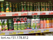 A supermarket display case with a wide range of drinks and yogurts. On the top shelf there are rows of bottles of Activia yogurt of different flavors: peach, raspberry, cereals and others. They are easily recognizable by their characteristic green packaging with bright fruit images. On the middle shelf there are various drinks in tetrapacks and plastic bottles: Big Mug with lemon flavor, Milk Time Cool with mint and lime or strawberry, as well as Actual drinks with fruit flavors - grapefruit and orange. On the shelves you can also see price tags with promotions and discounts. The photo vividly conveys the atmosphere of the supermarket, the abundance of goods and a wide selection of dairy and soft drinks. (2015 год). Редакционное фото, фотограф Анна Кривицкая / Фотобанк Лори