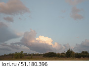 Large beautiful cumulus clouds in evening sunset sky above golden field, summer landscape. Стоковое фото, фотограф irisff / Фотобанк Лори
