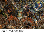 A collection of decorative plates with Egyptian motifs. Each plate is made in a unique style and decorated with traditional ornaments and images associated with the culture of Ancient Egypt. On them you can see pyramids, the Sphinx, pharaohs, chariots, priests and gods, as well as the famous images of Queen Nefertiti. The main colors are gold, bronze, copper and black, which emphasizes the sophistication and authenticity of the products.Such souvenirs are usually found in oriental markets or in tourist shops in Egypt. Photography perfectly conveys the atmosphere of oriental flavor and can be used to illustrate topics related to history, culture, tourism and arts and crafts. Стоковое фото, фотограф Анна Кривицкая / Фотобанк Лори