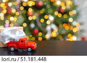 A small red car on the table with a Christmas gift and a fancy Christmas tree. Стоковое фото, фотограф Alexandra Aleroewa / Фотобанк Лори