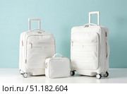 Three white travel suitcases including a small carry-on bag, shown in a minimalist studio with a light blue background, concept of travel. Стоковое AI-изображение, AI-художник Александра Рублева / Фотобанк Лори