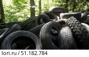 Discarded rubber tires accumulate in a forested area, posing significant risks to local ecology. The pollution disrupts wildlife habitats and contributes to environmental degradation. Стоковое фото, фотограф Громов Александр / Фотобанк Лори
