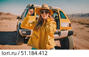 Happy woman wearing a yellow jacket and hat is seen standing in front of a yellow truck. Active woman appears to be posing for a photo or enjoying the view. Стоковое AI-видео, аниматор Данила Большаков / Фотобанк Лори