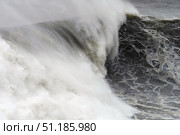 Massive winter wave surging with raw power, breaking against rocky coastline, highlighting nature's untamed marine force. Стоковое фото, фотограф Данил Руденко / Фотобанк Лори
