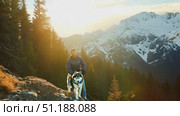 A person hikes alongside a Siberian husky, enjoying stunning mountain vistas and the warmth of a sunset over the landscape. Стоковое AI-видео, аниматор Данила Большаков / Фотобанк Лори