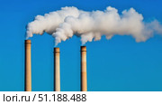 Three tall industrial chimneys release thick plumes of white smoke into the bright blue sky, symbolizing air pollution and industrial activity. The image captures the environmental impact of manufacturing and energy production. Стоковое AI-видео, аниматор Ксения Чунаева / Фотобанк Лори