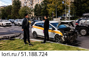 Мужчина держит паспорт и страховой полис. Аварии, катастрофы на дорогах. Дорожно-транспортное происшествие с участием такси. Повреждённый автомобиль, разбитый, обломки. Водители обсуждают вопросы денежной компенсации. Москва, 2025/ Редакционное фото, фотограф Iva Noel / Фотобанк Лори