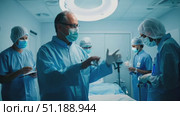 A team of medical professionals in scrubs meticulously prepares for surgery, focusing on their tasks and instruments in the sterile environment. Стоковое AI-видео, аниматор Данила Большаков / Фотобанк Лори