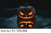Glowing jack-o'-lantern with cracked surface reflecting in dark water, creating eerie ambiance. Стоковое AI-видео, аниматор Данил Руденко / Фотобанк Лори